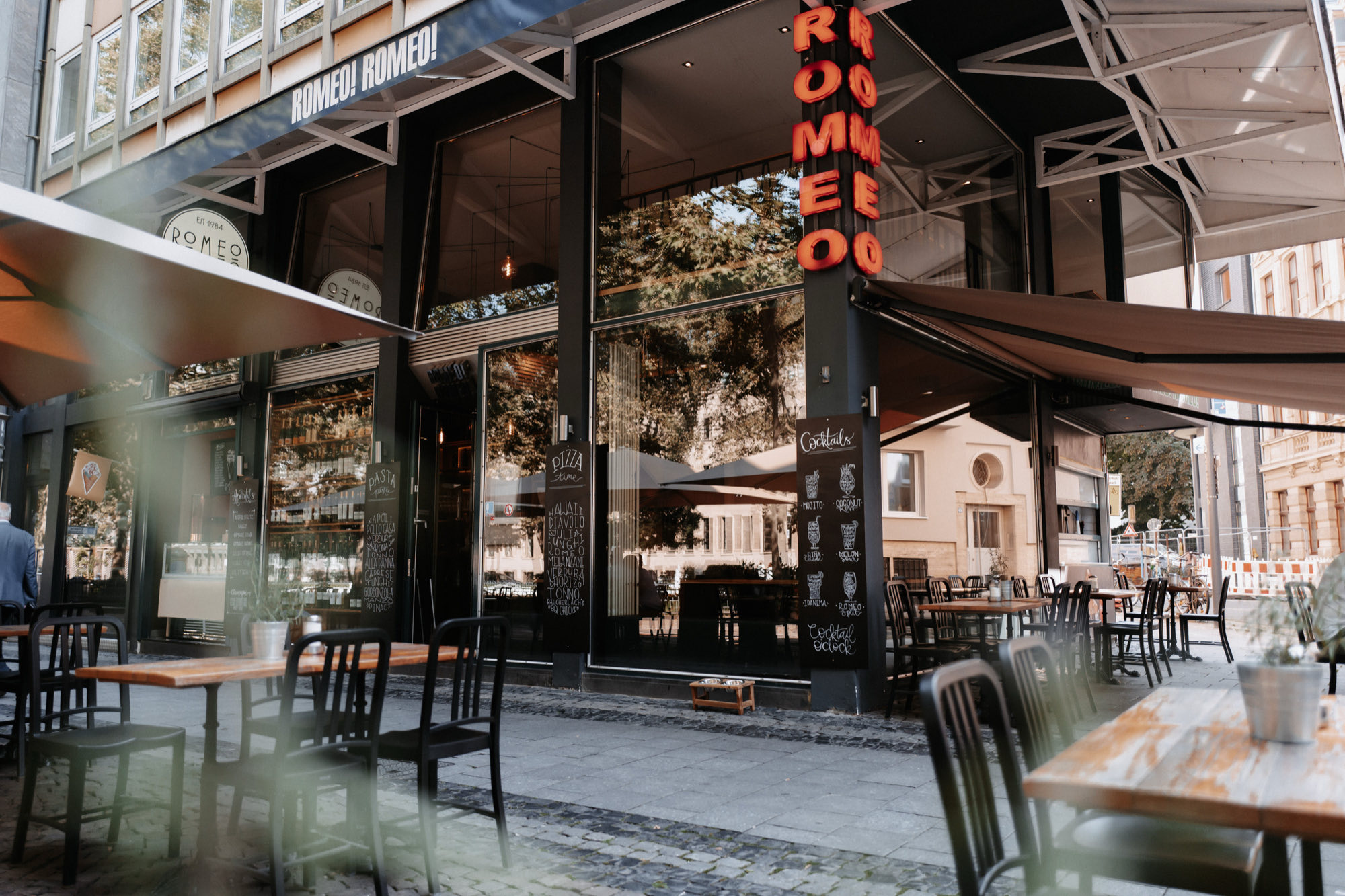 Fassade des Café RomeoRomeo mit Markise und Tischen auf dem Gehweg